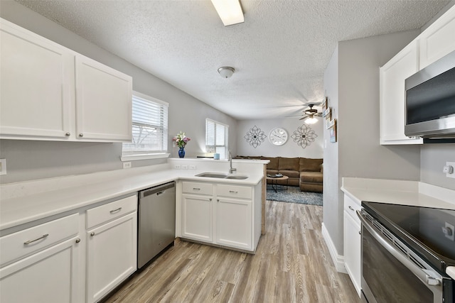 728 Oriole Dr, Saginaw, TX 76131 - kitchen featuring a peninsula, a sink, white cabinetry, light countertops, and appliances with stainless steel finishes