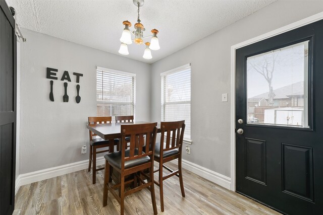 728 Oriole Dr, Saginaw, TX 76131 - dining area featuring a chandelier, light wood finished floors, a textured ceiling, and baseboards
