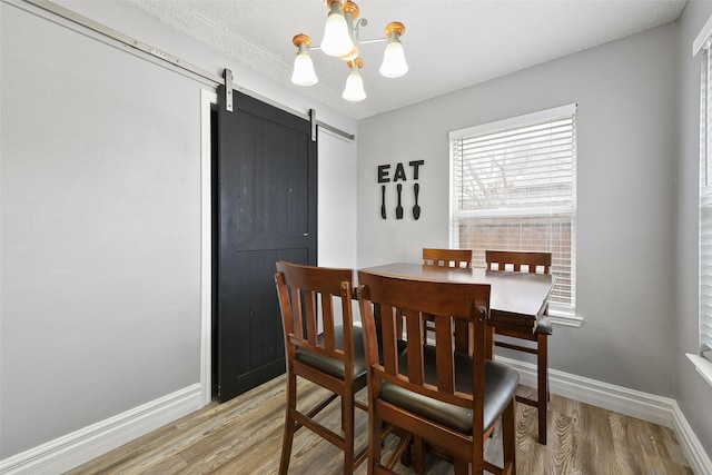 728 Oriole Dr, Saginaw, TX 76131 - dining room with a chandelier, a barn door, wood finished floors, and baseboards