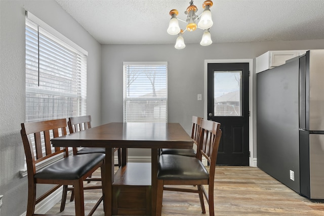 728 Oriole Dr, Saginaw, TX 76131 - dining space with light wood-style floors, a chandelier, and a textured ceiling