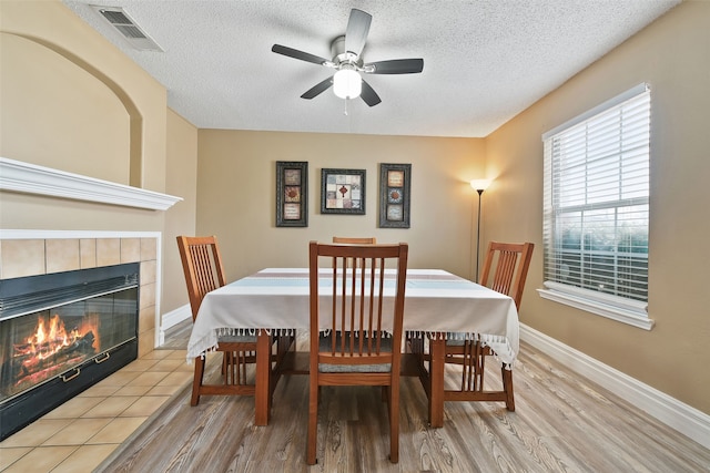 728 Oriole Dr, Saginaw, TX 76131 - dining space featuring a fireplace, visible vents, a textured ceiling, light wood-type flooring, and baseboards