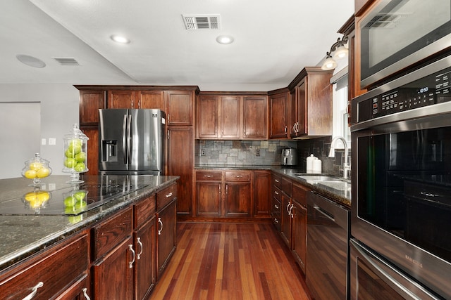 kitchen featuring decorative backsplash, visible vents, appliances with stainless steel finishes, and a sink