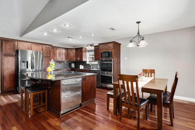 kitchen with dark wood-style flooring, stainless steel appliances, decorative backsplash, a warming drawer, and a chandelier