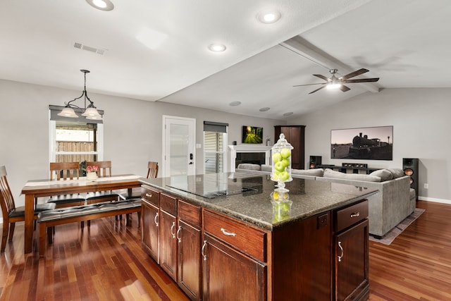 kitchen with visible vents, vaulted ceiling with beams, a tiled fireplace, dark wood-style floors, and black electric cooktop