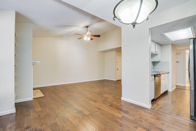 kitchen featuring lofted ceiling, hardwood / wood-style flooring, ceiling fan, stainless steel appliances, and white cabinets