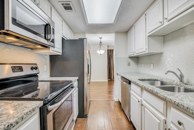 kitchen featuring stainless steel appliances, sink, pendant lighting, and white cabinets