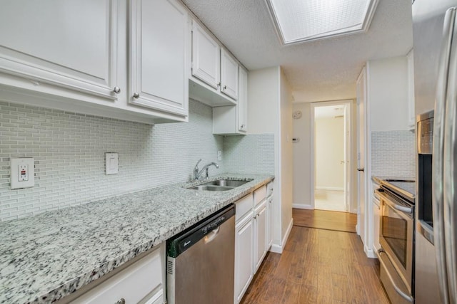 kitchen featuring sink, appliances with stainless steel finishes, white cabinetry, dark hardwood / wood-style floors, and light stone countertops