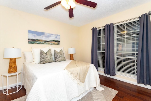 bedroom with a textured ceiling, dark wood-type flooring, and ceiling fan