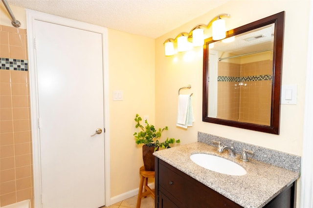 bathroom featuring tile patterned floors, tiled shower, vanity, and a textured ceiling