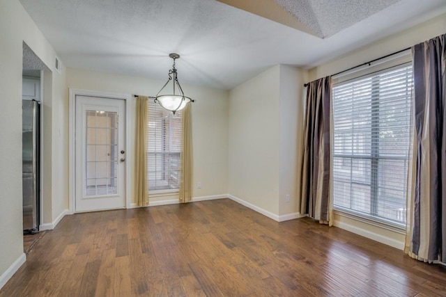 unfurnished dining area with dark wood-type flooring and a textured ceiling