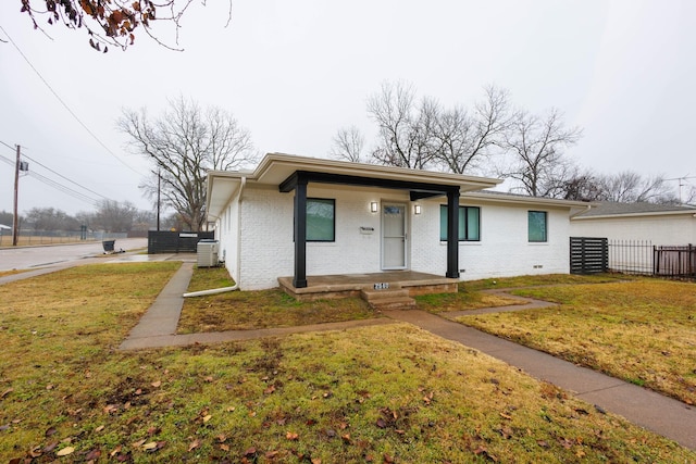 view of front of house with covered porch, a front lawn, and central air condition unit