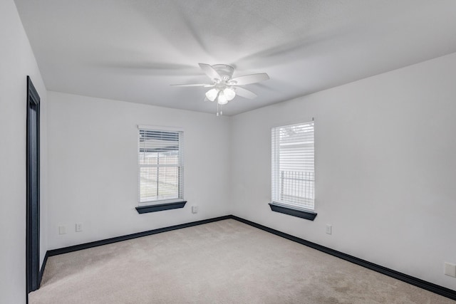 empty room featuring ceiling fan and light colored carpet