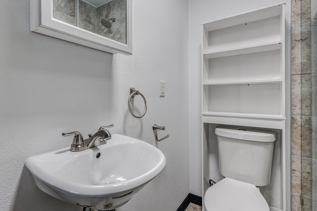 bathroom featuring sink, a shower, and toilet