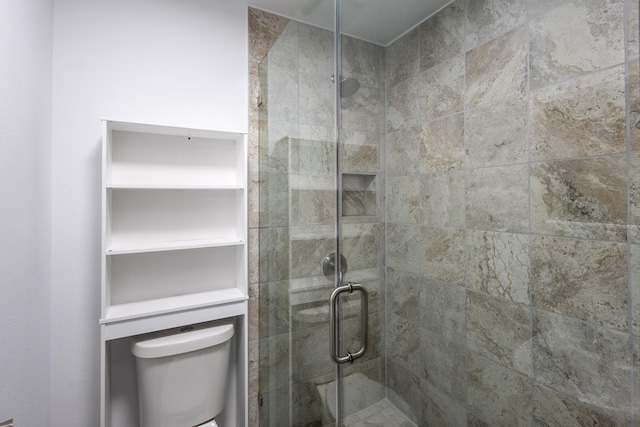 bathroom featuring toilet and a shower with door