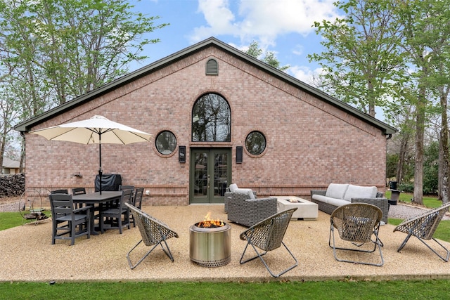 back of house featuring an outdoor living space with a fire pit, a patio, french doors, and brick siding