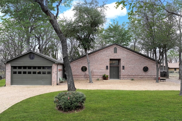 view of front of home featuring a garage, gravel driveway, brick siding, and a front lawn