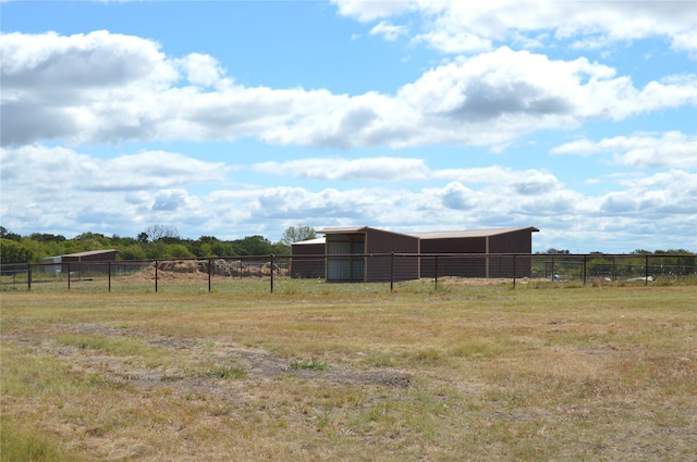 view of yard featuring a rural view, an outbuilding, fence, and an outdoor structure
