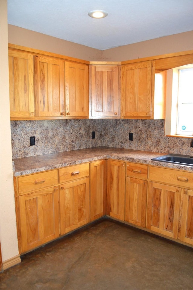kitchen featuring a sink, concrete floors, and tasteful backsplash