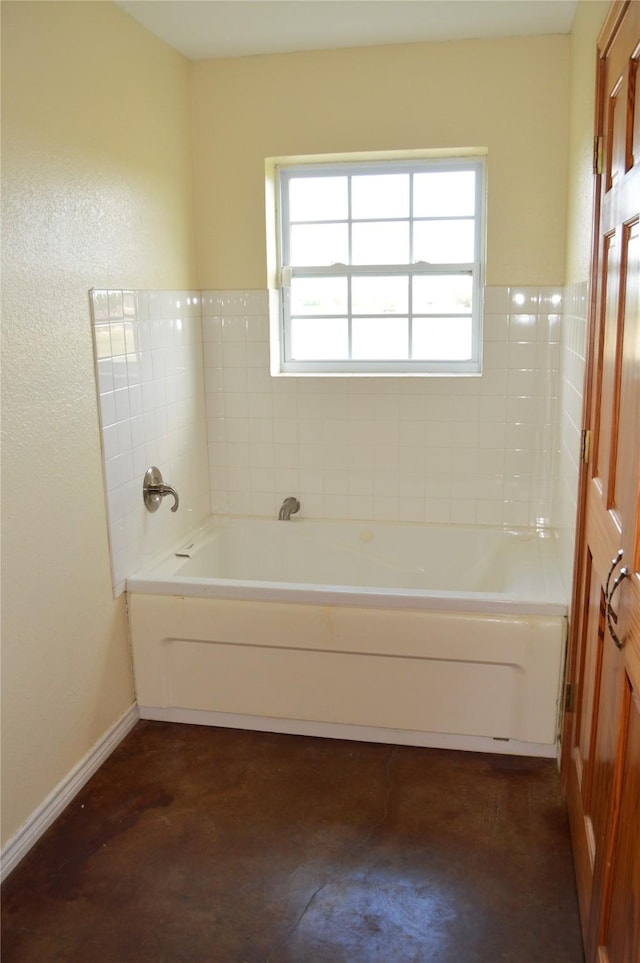 bathroom featuring a garden tub and baseboards