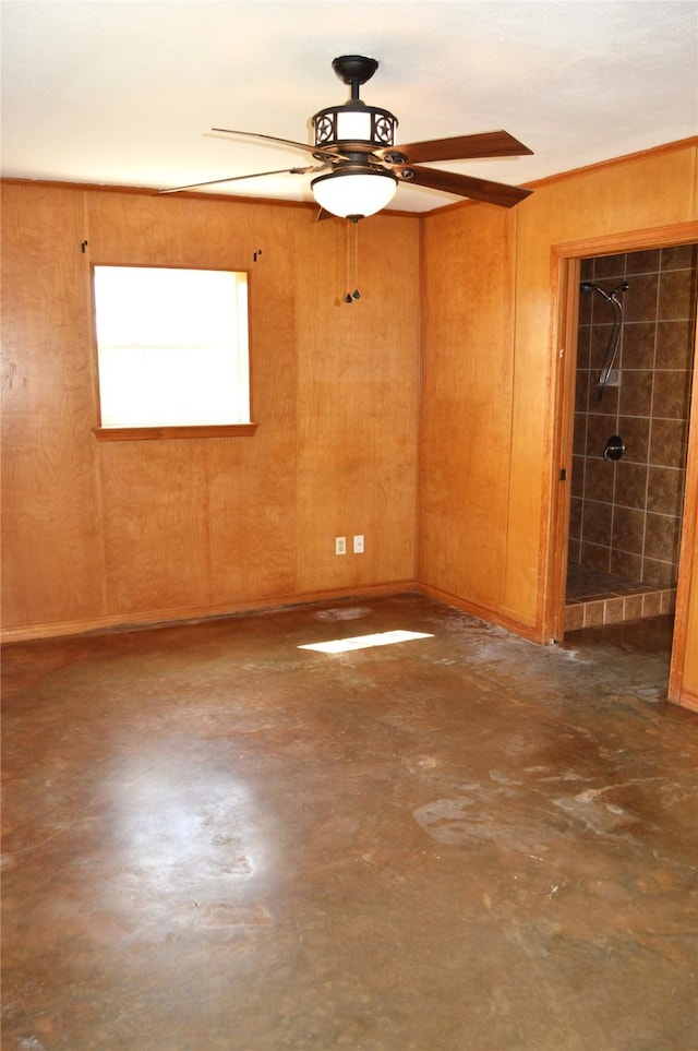 empty room featuring concrete flooring, a ceiling fan, and wood walls