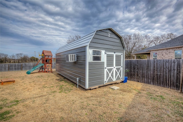 view of shed featuring an AC wall unit, a fenced backyard, and a playground