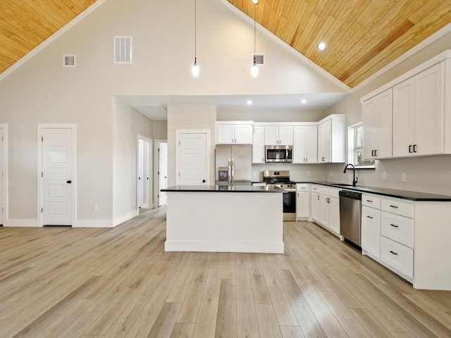 kitchen with appliances with stainless steel finishes, decorative light fixtures, white cabinetry, sink, and a center island