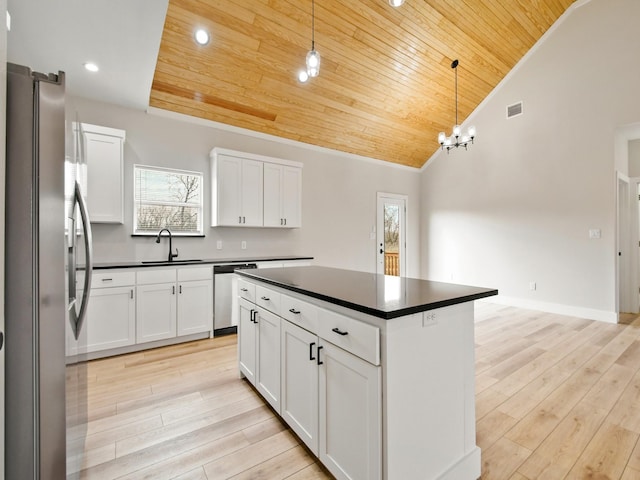 kitchen featuring sink, appliances with stainless steel finishes, white cabinets, a kitchen island, and decorative light fixtures