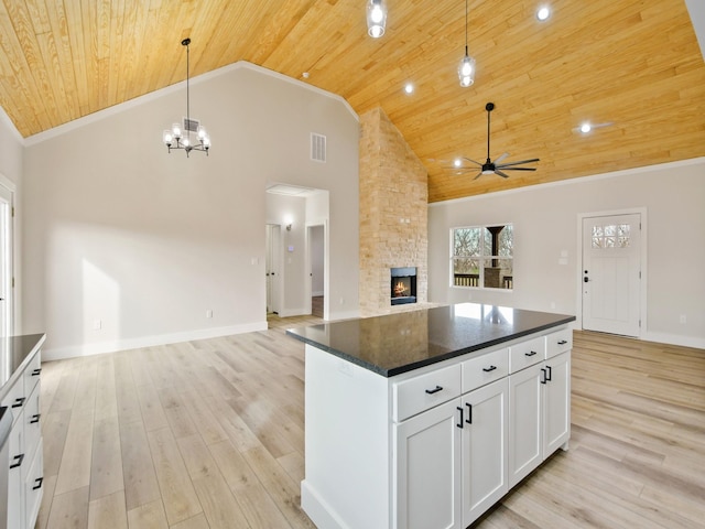 kitchen featuring decorative light fixtures, a center island, a fireplace, light hardwood / wood-style floors, and white cabinets