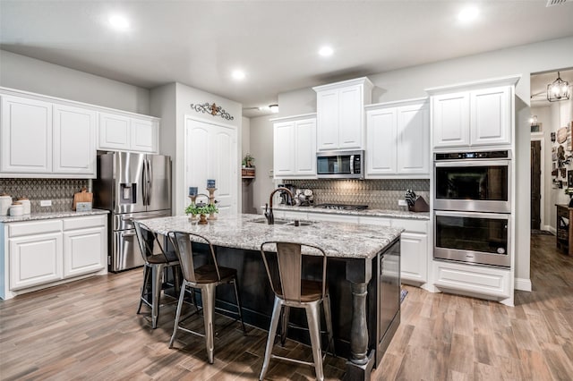 kitchen with white cabinetry, appliances with stainless steel finishes, a kitchen island with sink, and sink