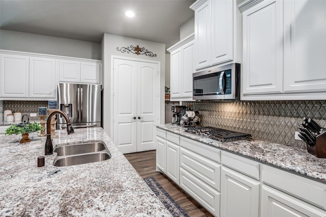 kitchen with appliances with stainless steel finishes, dark hardwood / wood-style floors, sink, backsplash, and white cabinets