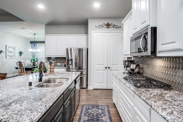 kitchen featuring appliances with stainless steel finishes, sink, white cabinets, and decorative light fixtures