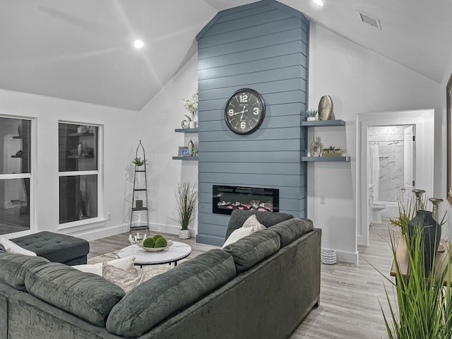 living area with a fireplace, lofted ceiling, visible vents, light wood-style flooring, and baseboards