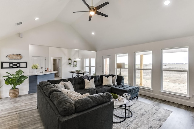 living area featuring high vaulted ceiling, recessed lighting, visible vents, and wood finished floors