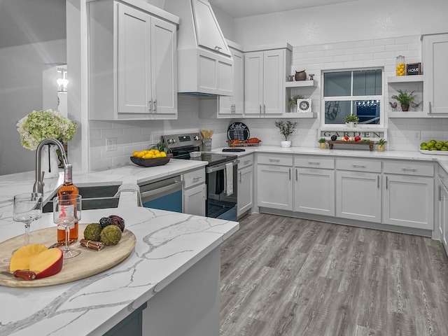 kitchen featuring appliances with stainless steel finishes, light stone countertops, wall chimney range hood, and open shelves