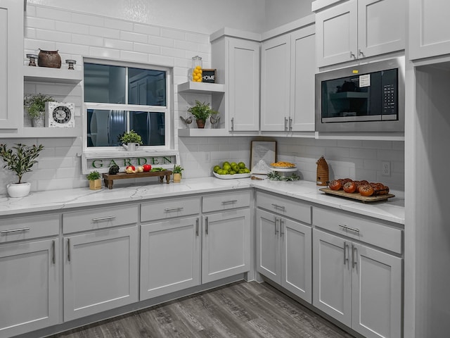 kitchen with built in microwave, light stone countertops, decorative backsplash, and open shelves