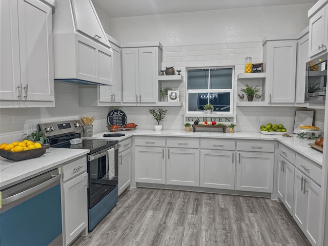 kitchen featuring open shelves, appliances with stainless steel finishes, light wood-style floors, light stone countertops, and wall chimney exhaust hood