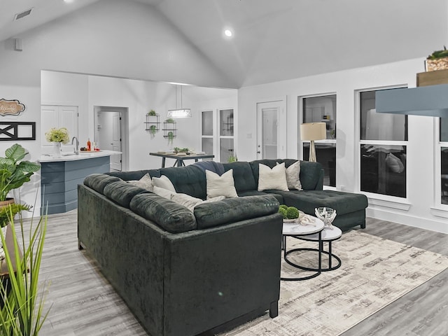 living area featuring recessed lighting, light wood-style floors, visible vents, and high vaulted ceiling