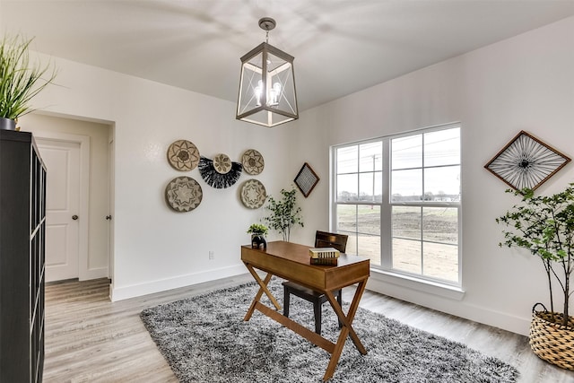 office space featuring a chandelier, light wood-style flooring, and baseboards