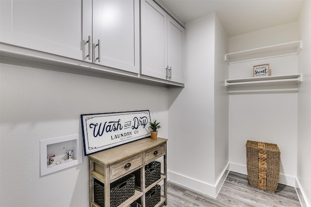 laundry area featuring cabinet space, baseboards, washer hookup, and light wood-style floors