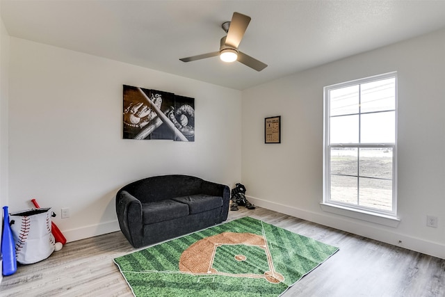 sitting room with a ceiling fan, baseboards, and wood finished floors