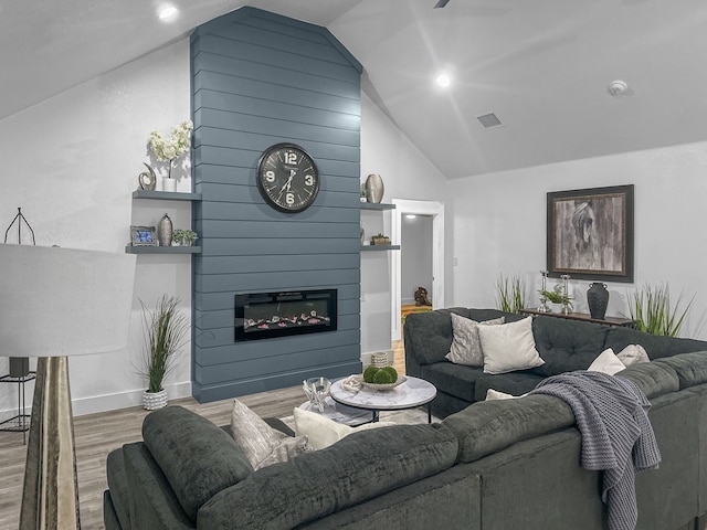 living room with a fireplace, wood finished floors, visible vents, baseboards, and vaulted ceiling