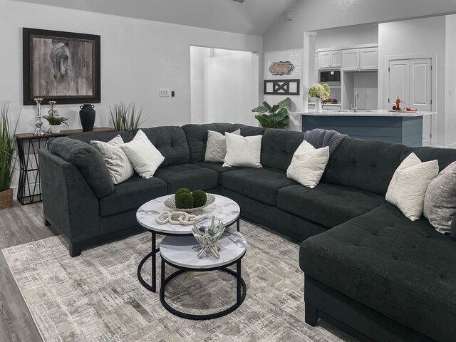 living area featuring light wood-type flooring, visible vents, and vaulted ceiling