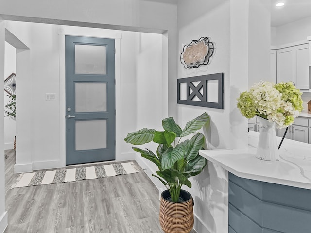 foyer entrance featuring baseboards, wood finished floors, and recessed lighting