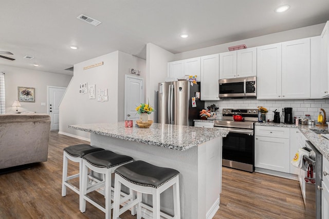 kitchen featuring tasteful backsplash, visible vents, stainless steel appliances, and wood finished floors