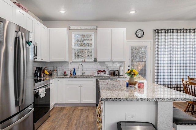 kitchen with a breakfast bar, decorative backsplash, stainless steel appliances, and a sink