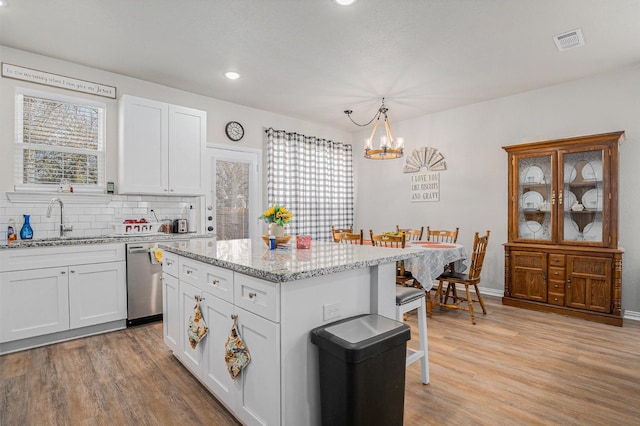 kitchen featuring light wood finished floors, a wealth of natural light, visible vents, dishwasher, and a sink