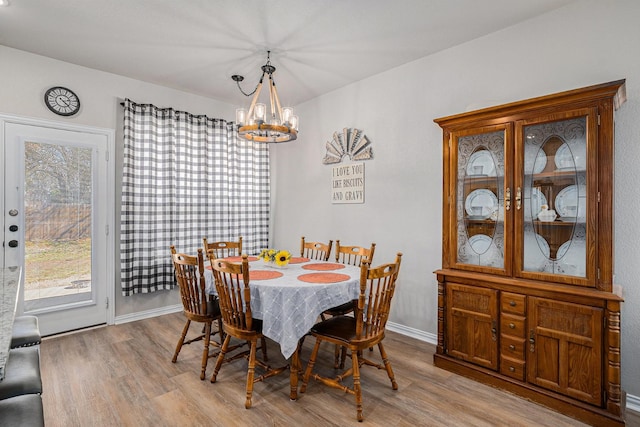 dining room featuring baseboards, an inviting chandelier, and light wood-style floors