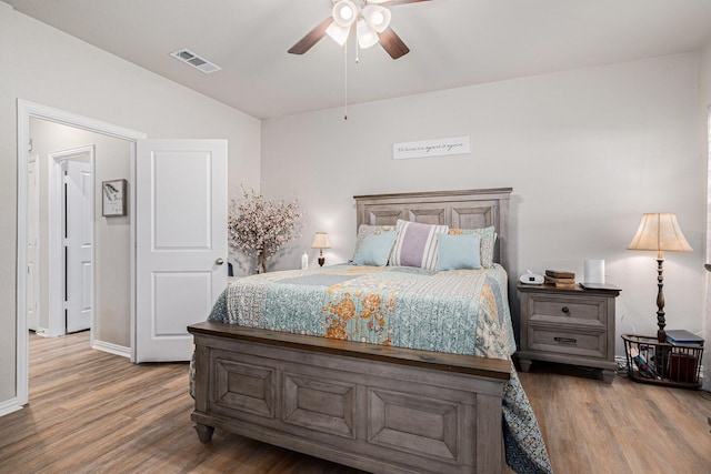 bedroom with lofted ceiling, ceiling fan, wood finished floors, and visible vents