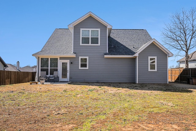 rear view of house with a yard, roof with shingles, and a fenced backyard