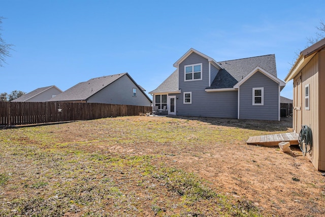 back of property featuring a yard, roof with shingles, and a fenced backyard